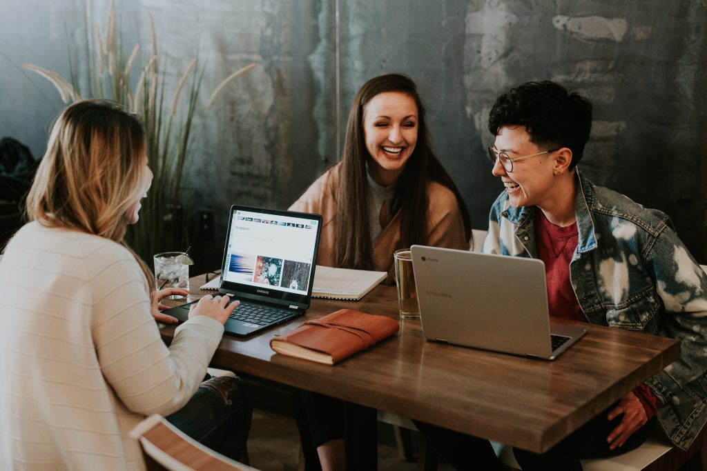 Three people sitting around a table and laughing