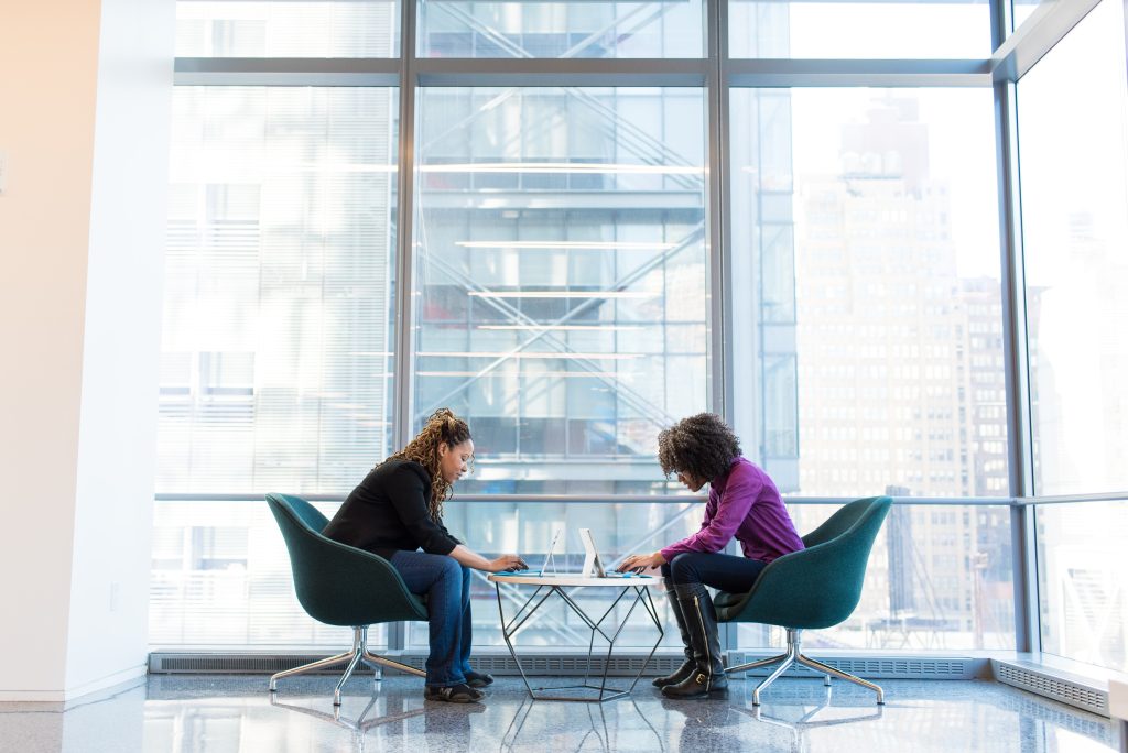 Two women sitting opposite each other using laptops