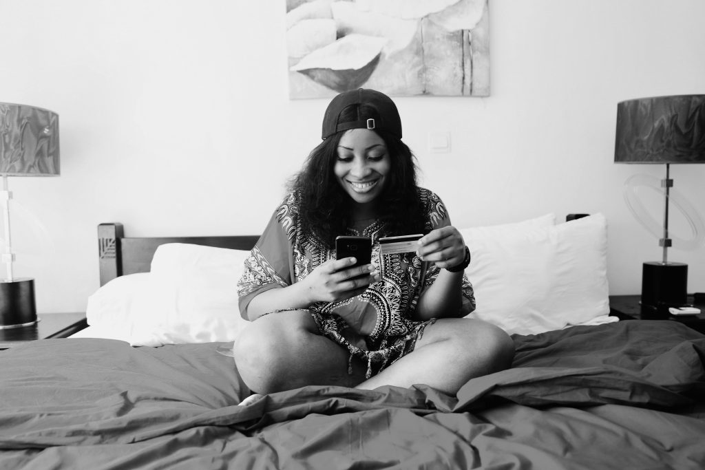 Black woman holding her card and phone, smiling