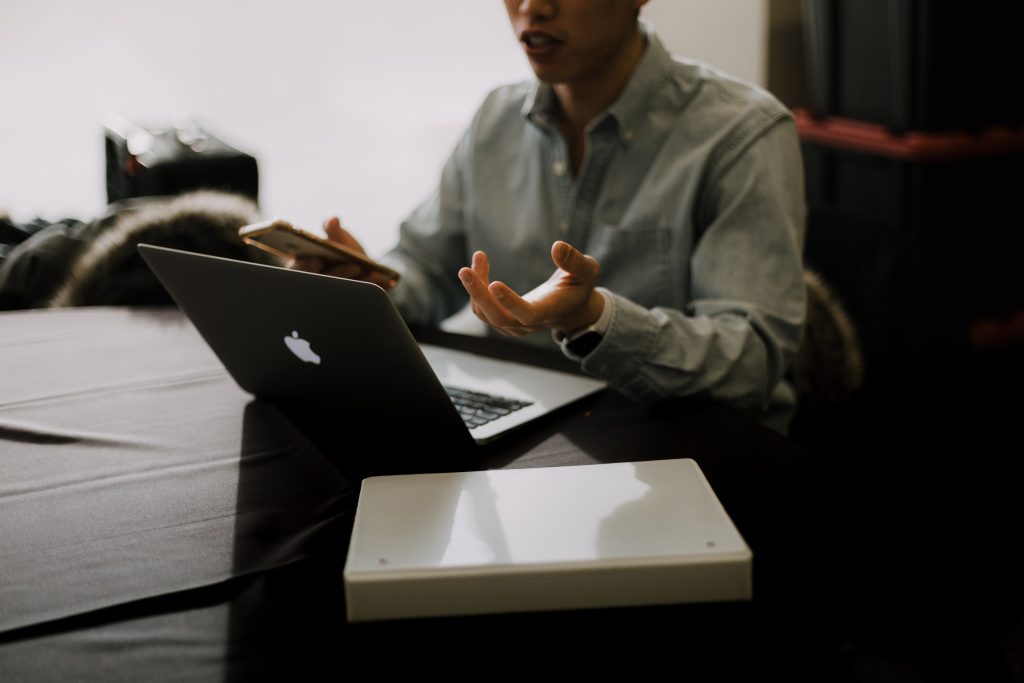 A man sitting at a table with a laptop in front of him.