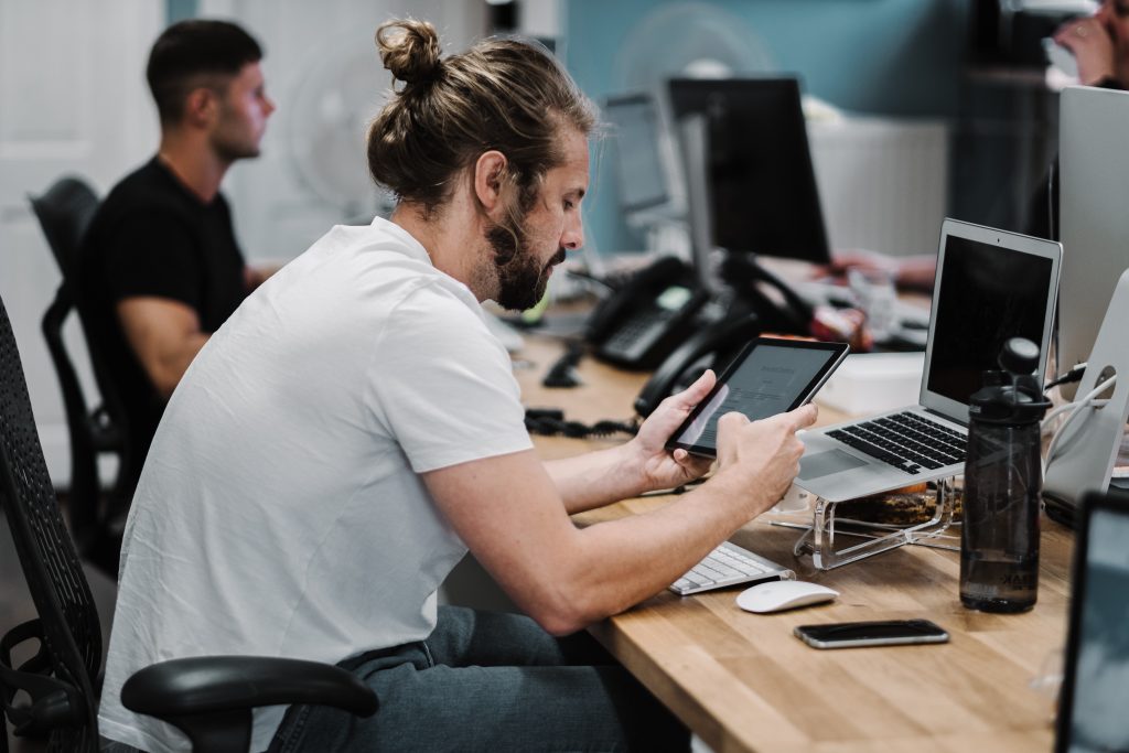 Man holding turned on ipad in front of turned off Macbook air