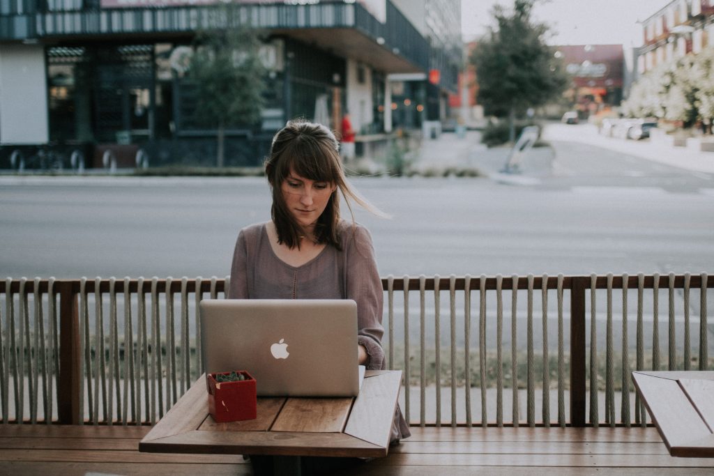 Woman sitting on a bench in front of a MacBook