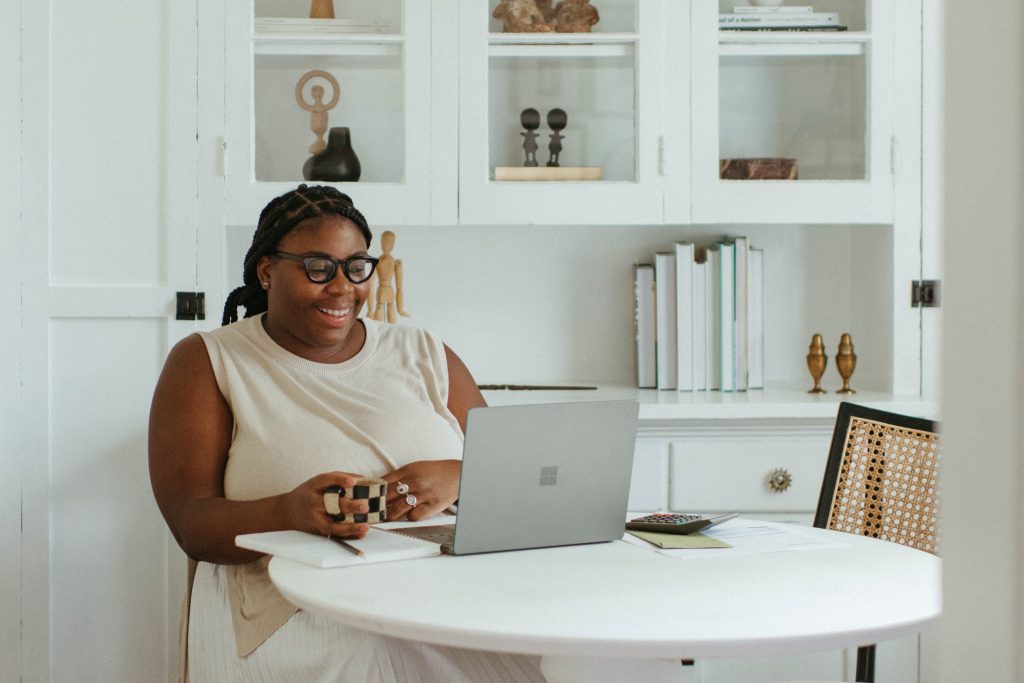 A woman sitting in front of a round table with a laptop on top