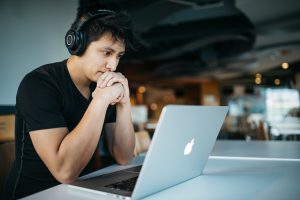 Man wearing headphones, sitting in front of a MacBook