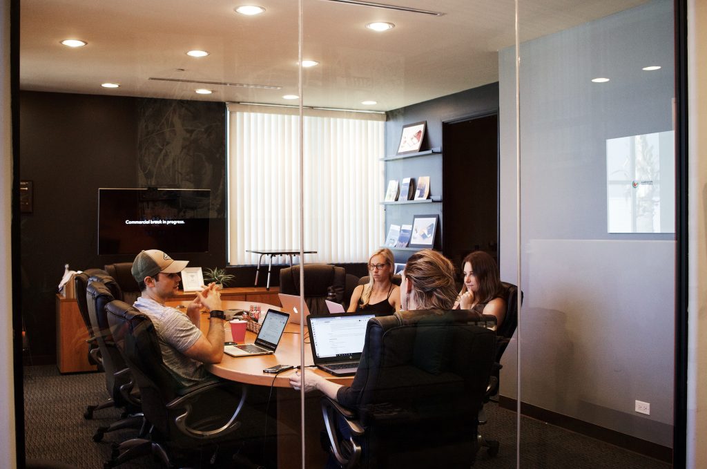 People sitting near table with open laptops