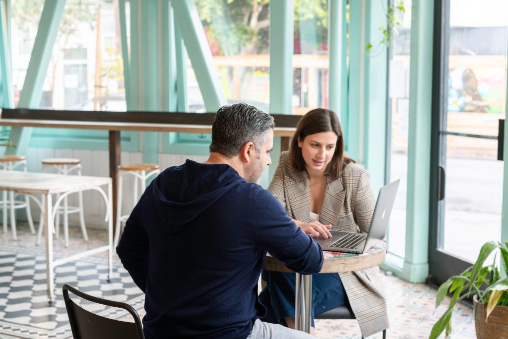 Man in a black long sleeve shirt sitting beside a woman with a computer