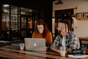 Man and woman sitting at a table using a MacBook